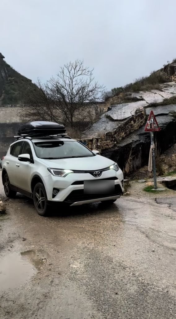 Coche en el camino de tierra junto a la presa, con charcos